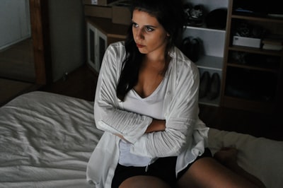女人穿着白色开衫坐在床上
